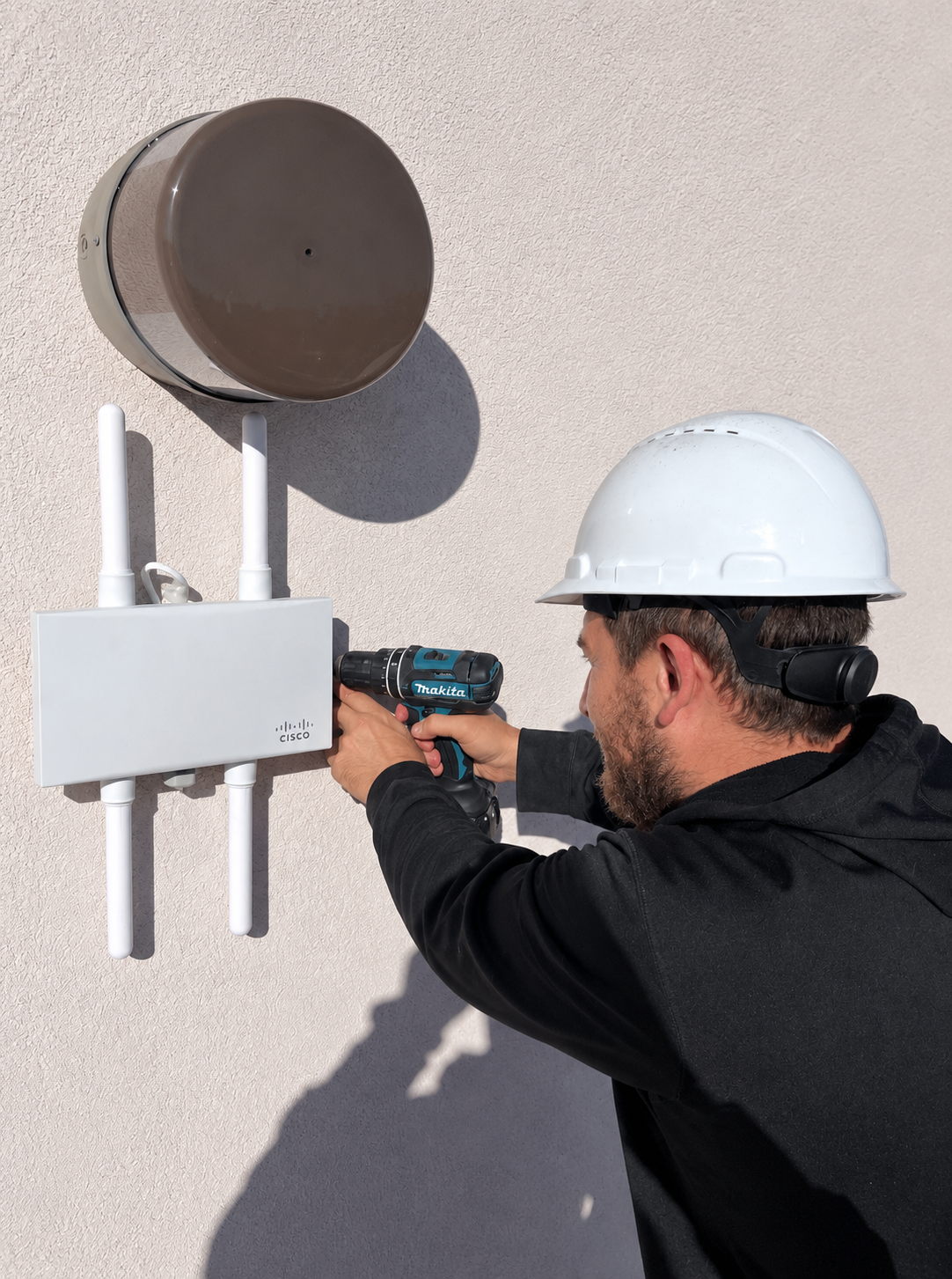 Technician installing an outdoor Cisco wireless access point for a commercial network